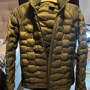 Grön dunjacka från Peak Performance - Säljer en snygg grön dunjacka från Peak Performance. Jackan har en quiltad design med dragkedja framtill och långa ärmar. Perfekt för kyliga dagar och håller dig varm och bekväm. Passar både till vardags och utomhusaktiviteter.