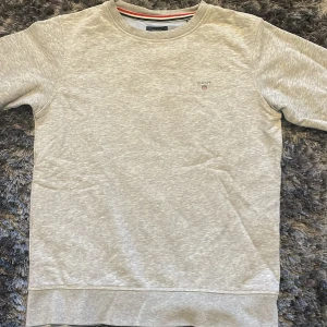 Grå sweatshirt från GANT - Säljer en stilren grå sweatshirt från GANT med broderad logga på bröstet. Den är aldrig använd så den är i bra skick! 
