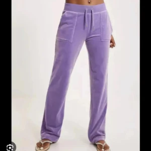 Lila mjukisbyxor med fickor - Säljer ett par lila juicy couture mjukisbyxor med raka ben och stora fickor framtill. Byxorna har dragsko i midjan och är perfekta för en avslappnad stil. Supermjuka och sköna att ha på sig! Använda typ 6 gånger och är sparsamt använda 💓köpta 2022 för 1200 i butik💓pris kan diskuteras vid snabb affär💓