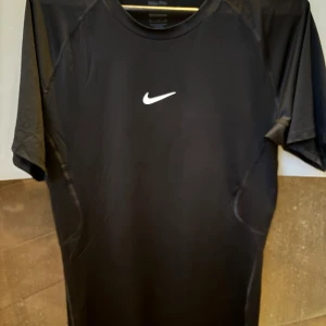 Svart Nike Pro Dri-FIT compression t-shirt  - Säljer en svart Nike Pro Dri-FIT t-shirt med klassisk vit swoosh-logga på bröstet. T-shirten är tillverkad i ett syntetmaterial som andas och har en tight passform, perfekt för träning eller sport.