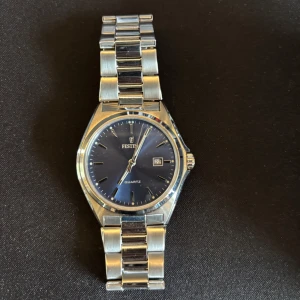 Festina herrklocka med blå urtavla - Stilren herrklocka från Festina med blå urtavla och datumvisning. Klockan har ett armband i silverfärgad metall och levereras i originalask med garantibevis. Perfekt accessoar för dig som gillar klassisk design.