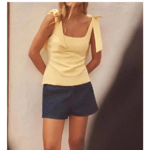 Gul ärmlös topp med knytband - Snygg gul ärmlös topp med knytband på axlarna. Toppen är i storlek M men skulle säga att den passar S också. helt ny och aldrig använd, prislappen finns kvar🩷