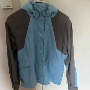 Blå och grå skidjacka från Helly Hansen - Säljer en snygg blå och grå vindjacka från Helly Hansen.🩷