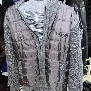 Hugo Boss cardigan - Snygg grå cardigan från Hugo Boss med quiltade detaljer och dragkedja. Jackan har en mix av material med stickade ärmar och rygg, samt ett mönstrat foder. Perfekt för kyligare dagar. Storlek XL men känns som M-L