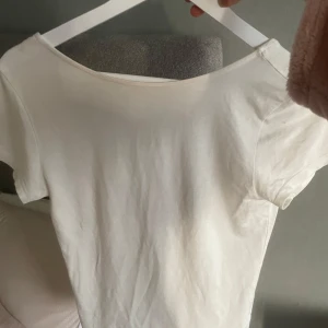 Vit omlottopp med knytband - Säljer en vit omlottopp med korta ärmar och knytband i midjan. Toppen har en djup v-ringning och är gjord i ett mjukt material som känns skönt mot huden. Perfekt att styla med jeans eller kjol.