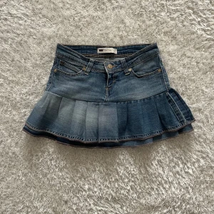 Jeanskjol med volang - Lågmidjad jeanskjol omsydd från ett par jeans. Midjemått tvärsöver- 34cm  Längd- 32cm 