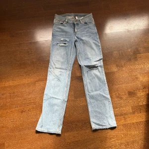Ljusblå jeansbyxor från Weekday - Ljusblå jeansbyxor från Weekday i modellen Twig. Byxorna har bootcut ben, klassisk femficksdesign och slitna detaljer på låret och knät. Perfekta för en avslappnad och trendig look. Jeansen är mer bootcut på kroppen än på bilden. Hålen är gjorda själv. Bra skick!💕