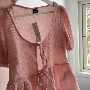 Ljusrosa blus - Supersöt ljusrosa blus från Gina Tricot med korta puffärmar och knyt framtill. Perfekt till sommaren😍 Helt oanvänd med prislapp kvar 🤍