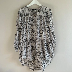 Mönstrad blus/ tunika från H&M - Snygg och luftig blus/ tunika från H&M med ett djurinspirerat mönster i svart och cremefärg. Ärmar går att vika upp/ fästa i 3/4. Rökfritt hem. Rensar garderoben så kika gärna på övriga annonser!