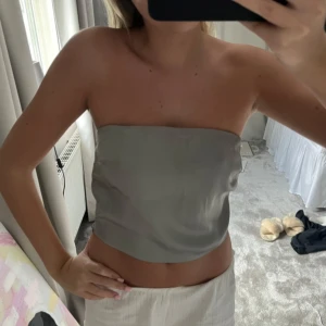 Grå tubtopp - Snygg grå tubtopp i ett slätt och stilrent material. Perfekt för varma dagar eller som en del av en lager-på-lager-look. Enkel och elegant design som passar till många olika outfits.