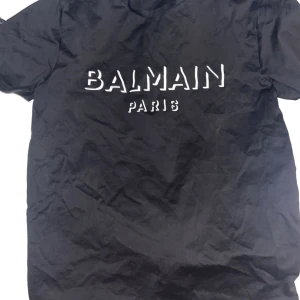 Balmain - Säljer en svart t-shirt från Balmain Paris med vit logga tryckt på bröstet. Klassisk passform och rund halsringning. Perfekt för dig som gillar stilrena märkesplagg. Äkta såklart:) storlek L men har en passform som M