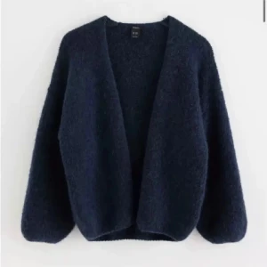 Mörkblå stickad kofta  - Mysig och enkel mörkblå stickad kofta med lång ärm och öppen front. Passar till många olika outfits. Tjockt och fluffigt material som känns skönt mot huden.