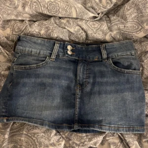 Blå jeanskjol - Snygg blå jeanskjol med klassisk femficksdesign och knappstängning fram. Perfekt för en avslappnad stil. Passar bra till både sneakers och sandaler.