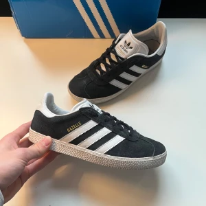 Adidas Gazelle i svart och vit - Snygga Adidas Gazelle sneakers i svart mocka med vita detaljer och klassiska tre ränder. De är i perfekt skick. Fråga om du har frågor