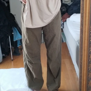 Olivgröna vida byxor i bomull - Säljer ett par snygga olivgröna lågmidjade byxor med rak och loose passform. Byxorna har resår i midjan och vid anklarna och är tillverkade i ett mjukt bomullsmaterial. Perfekta för en avslappnad stil och har fickor både fram och bak. Finns här om du undrar något! ❤️