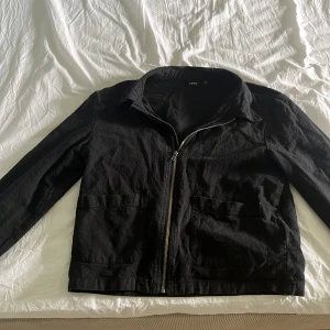 Svart jacka med dragkedja från LMTD - Säljer en svart jacka från LMTD i storlek XS. Jackan har klassisk krage, två stora fickor framtill och stängs med dragkedja. Passar perfekt till vår och höst. Enkel och stilren design som är lätt att matcha.