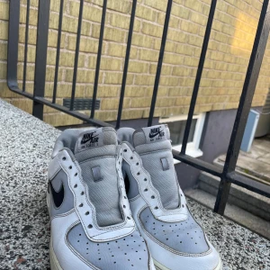 Nike Air Force 1 i grått och svart - Säljer ett par klassiska Nike Air Force 1 sneakers i grått me svart logga. Dessa är använda men nu bara stått ett tag o inte har någon nytta så vill bli av med dem!