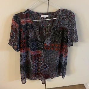 Genomskinlig blus i blått och rött massor med mönster - 44 passar en med storlek 42 och XL