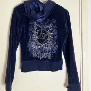 Mörkblå y2k zip up  - Mörkblå velour hoodie från Lipsy med glittrig broderad design och strassdetaljer på ryggen. Jackan har dragkedja, huva med satinband och fickor framtill. Liknar juicy couture mycket🤩storlek M men skulle säga att den passar bäst på S eller liten M!🥰