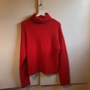 Röd stickad polotröja från H&M - Säljer en snygg röd stickad polotröja från H&M. Tröjan har en hög polokrage och långa ärmar, perfekt för kyliga dagar. Den är ribbad vilket ger en fin textur och stil. Passar utmärkt till både jeans och kjol. Använd en gång. ‼️pris kan diskuteras‼️