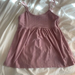 Rosa ärmlös klänning - Söt rosa klänning med smala axelband och ett fint broderat mönster. Perfekt för varma sommardagar. Klänningen har en luftig passform och är tillverkad i ett mjukt material.