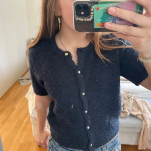Mörkblå kofta med korta ärmar - Säljer en mysig mörkblå kofta med korta ärmar och fina guldfärgade knappar. Perfekt för en stilren look. Passar bra till jeans eller kjol. Endast använd fåtal gånger❣️