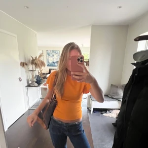Orange kortärmad topp - Säljer en snygg orange kortärmad topp med en tight passform. Perfekt för en färgglad och stilren look. Passar bra till jeans eller kjol för en avslappnad stil🩵. 
