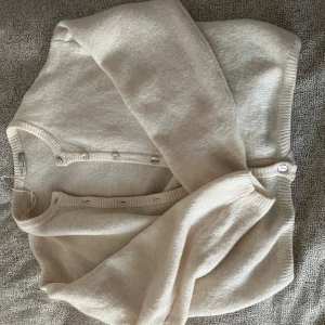 Beige kofta från Gina Tricot - Mysig beige kofta från Gina Tricot i mjukt material. Koftan har långa ärmar, rund halsringning och knäppning framtill med små knappar. använd 1 gång och inte mer pga att jag inte giller hur den sitter vid midjan 😅