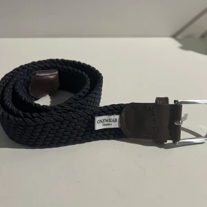 Flätat bälte från One wear - Säljer detta bälte då den inte användes. Den är 80 cm och i ett mycket bra skick. Riktigt snyggt och är passar bra!
