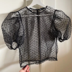 Topp från Zara - Säljer en svart transparent blus från Zara med puffiga trekvartsärmar och små prickar i tyget. .