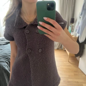 Stickad vinröd/lila kofta med kort ärm från Vero Moda - Stickad grå kofta från Vero Moda med korta ärmar och dubbelknäppning framtill. 