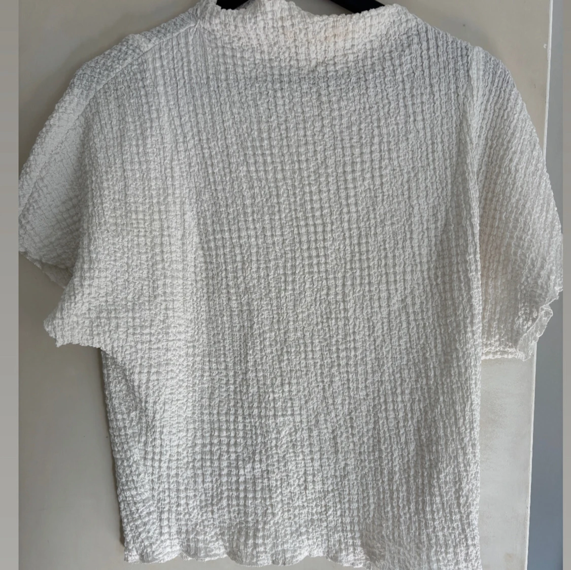 Vit kortärmad blus med struktur och figur sydd med höghals