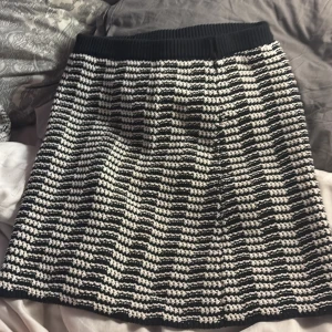 Svartvit stickad kjol från H&M - Säljer en svartvit stickad kjol från H&M i storlek S. Kjolen har ett randigt mönster och bred, ribbad midja för extra komfort. Den är kort och har en mjuk, grovstickad känsla som gör den både snygg och chill.