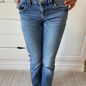 Blå jeans från Gina Tricot, stl 152 - Snygga blå jeans från Gina Tricot i storlek 152. Modellen har klassisk femficksdesign, kontrastsömmar och rak passform med lätt utsvängda ben. Jeansen är tillverkade i mjukt denimtyg och har normal midja med knapp och dragkedja framtill.