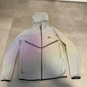 Grå Nike Tech Fleece  - Nike Tech Fleece hoodie i ljusgrått med svarta detaljer och dragkedja hela vägen. Använd fåtal gånger så gott som ny. 