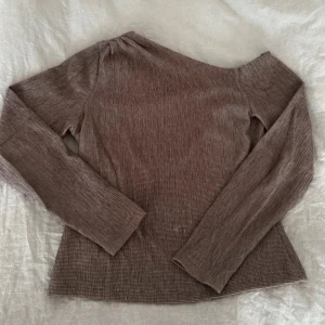 Brun asymmetrisk offshoulder topp från NA-KD - Säljer en brun offshoulder topp från NA-KD i storlek S. Liten skavank som visas på sista bilden