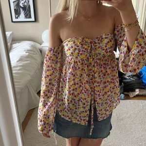 Blommig offshoulder blus med snörning - Supersöt blommig offshoulder blus med långa, vida ärmar och snörning framtill. Materialet är tunt och lite genomskinligt i ärmarna och ”magen”. 💕💕💕💕☺️