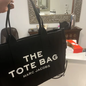 Svart shoppingväska Marc Jacobs - Säljer en svart tote bag från Marc Jacobs. Väskan har två långa handtag och är tillverkad i slitstark bomull. Perfekt storlek för att få plats med allt du behöver och har en stilren, boxig form.
