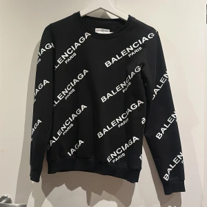 Svart sweatshirt - Svart sweatshirt med vit logotyp tryckt över hela tröjan. Rund hals, ribbade muddar och långärmad. 