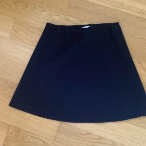 Svart kortkjol från Pieces - Enkel och stilren svart kortkjol från Pieces i A-linjeformad modell. Kjolen är helsvart utan mönster och har en klassisk, clean look som är lätt att matcha med olika toppar och jackor.