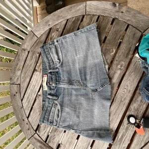 Levi's jeanskjol slim straight blå - Snygga jeansshorts från Levi's modell 514 Slim Straight i klassisk blå tvätt. Gjorda av 100% bomull med rå kant och fem fickor. Lowwaist passform och slitna detaljer för en chill vibe. Perfekta för sommarens häng och festivaler.
