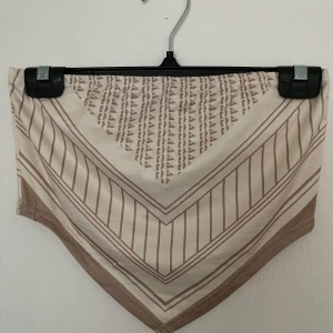 Beige mönstrad topp från SHEIN - Snygg beige topp från SHEIN i storlek XS med geometriskt mönster i bruna toner. Toppen har en trekantig form och är tillverkad i ett mjukt syntetmaterial som känns skönt mot huden. 