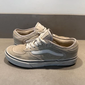 Beige Vans Old Skool sneakers - Säljer ett par riktigt nice beige Vans sneakers med klassisk vit sidorand och snörning. Skorna har en låg profil, rund tå och platt sula. Materialet är mocka och textil, med 66/99 präglat på hälen. Skriv gärna frågor om skorna.