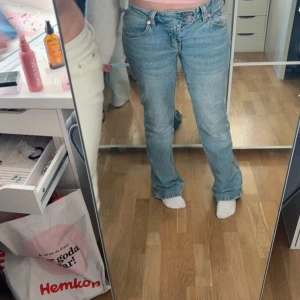 Bootcut ljusblå jeans med broderi - Säljer ett par ljusblå bootcut jeans med snyggt broderat mönster på bakfickan. Jeansen har klassisk femficksdesign, låg midja och är tillverkade i mjukt denim. Perfekta för dig som gillar en chill och trendig stil.