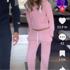 Ljusrosa hoodie med huva och snörning och byxor - Säljer en ljusrosa hoodie med huva och vit snörning.Och byxor, Russemerch, fint skick men finns nån liten fläck på byxorna-går troligen bort i tvätten, inget som jag tycker stört 