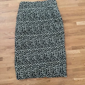 Leopardmönstrad långkjol i beige och svart - Säljer en snygg långkjol med leopardmönster i beige och svart. Kjolen har rak passform och är fodrad med vitt tyg på insidan. Perfekt för dig som vill sticka ut med ett djuriskt print och gillar trendiga detaljer.
