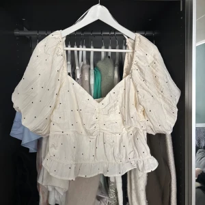 Vit prickig blus med puffärm - Supersöt vit blus med svarta prickar och stora puffärmar. Storlek L!! Säljer eftersom har två!! 