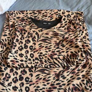 Leopardmönstrad klänning från Splash - Snygg ärmlös klänning från Splash i leopardmönster med beige och svarta toner. Modellen är figurnära upptill och har en lätt utsvängd kjol. Perfekt för dig som vill sticka ut med ett djuriskt print. Materialet känns mjukt och följsamt mot huden.