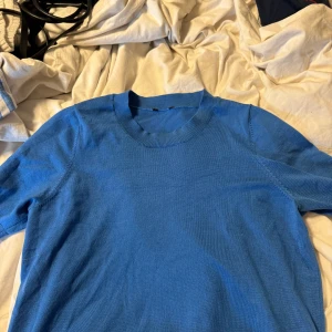 Lindex tröja - Snygg blå tröja med rund hals och korta ärmar, tillverkad i mjuk Tencel lyocell-blandning. Passformen är normal och materialet känns skönt mot huden. Perfekt för dig som gillar stilrena och enkla plagg med en fräsch färg.