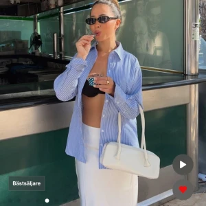 Blåvit randig oversized skjorta - Snygg oversized skjorta med blå och vita ränder, klassisk krage och knappar framtill. Skjortan har långa ärmar med breda manschetter och är tillverkad i mjuk bomull. Perfekt för en chill och trendig look. Helt ny, lapp kvar